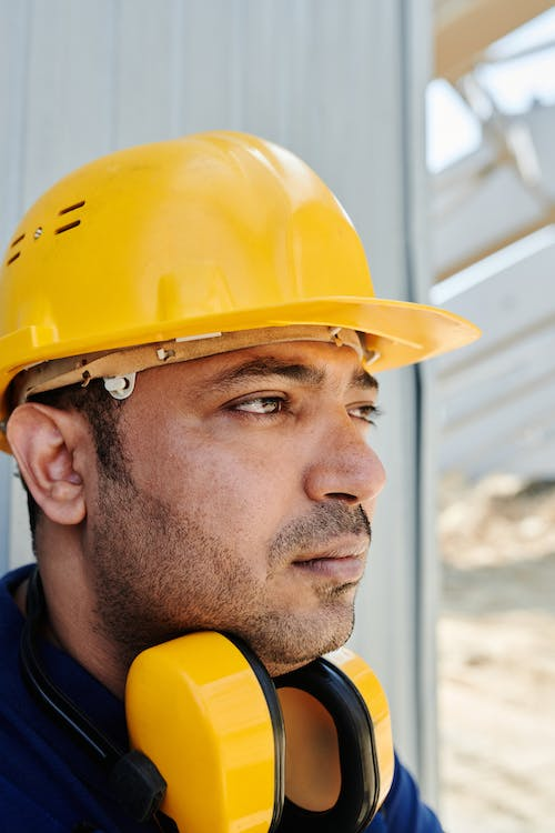 a person wearing a yellow hard hat and noise-canceling headphones