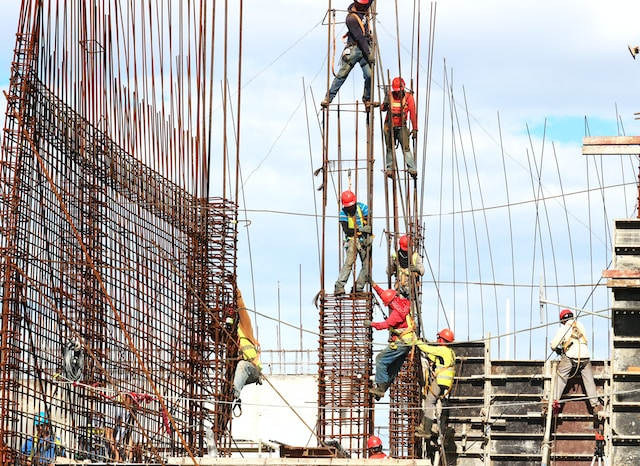Multiple workers installing reinforcing bars on a construction site.